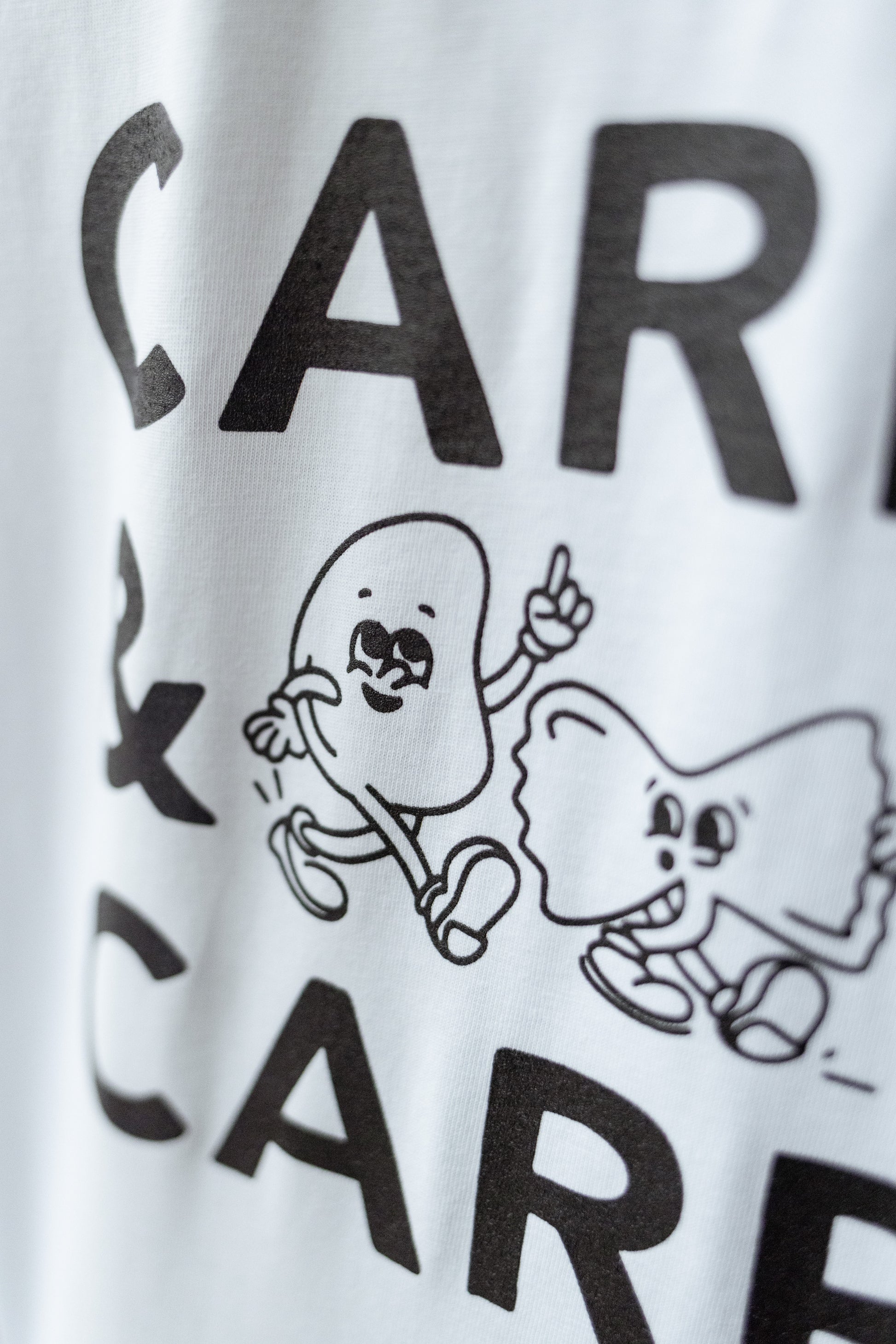Detailaufnahme vom weißen T-Shirt mit schwarzer „Carbs“ Illustration