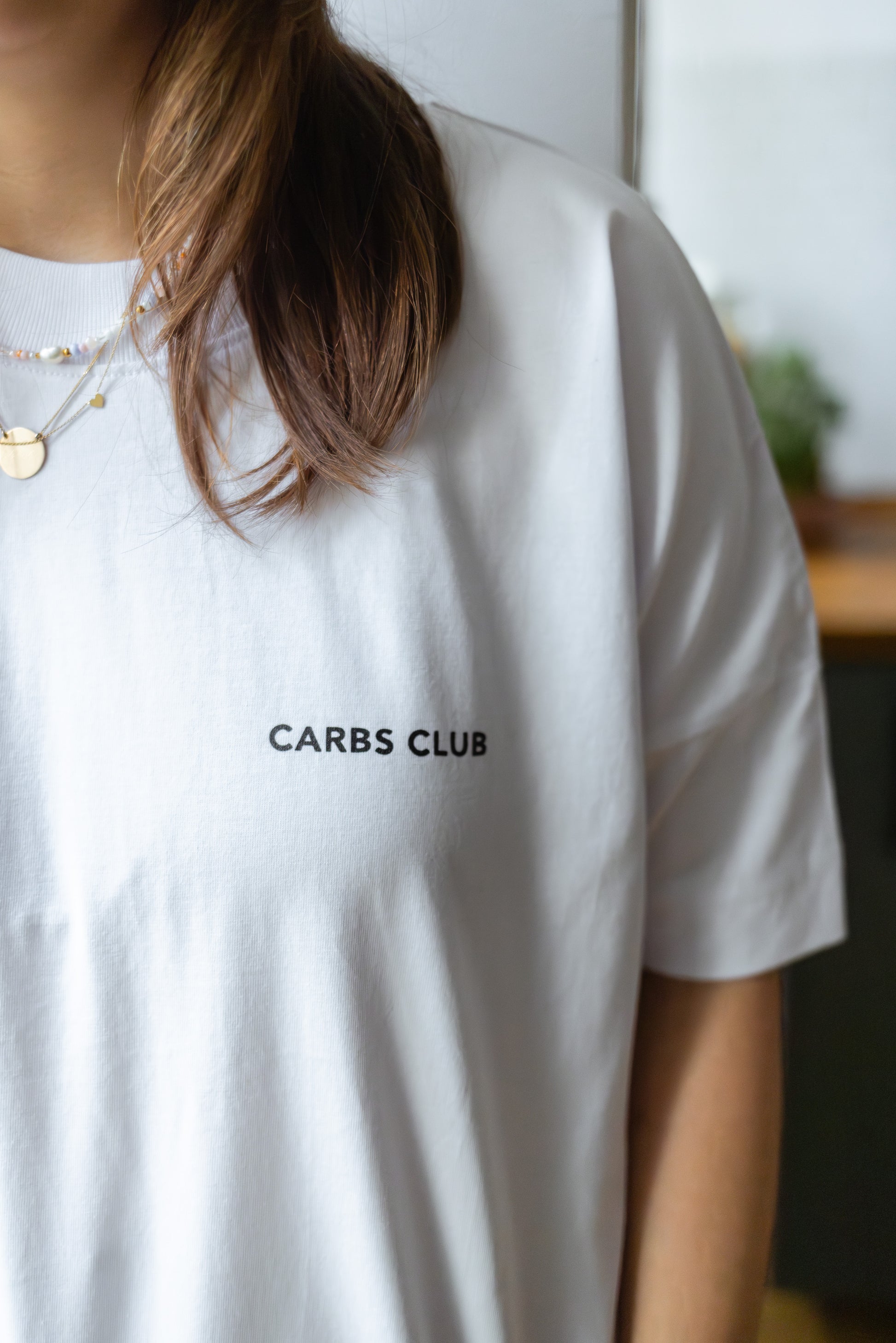 Detailaufnahme vom weißen T-Shirt mit schwarzer „Carbs“ Illustration